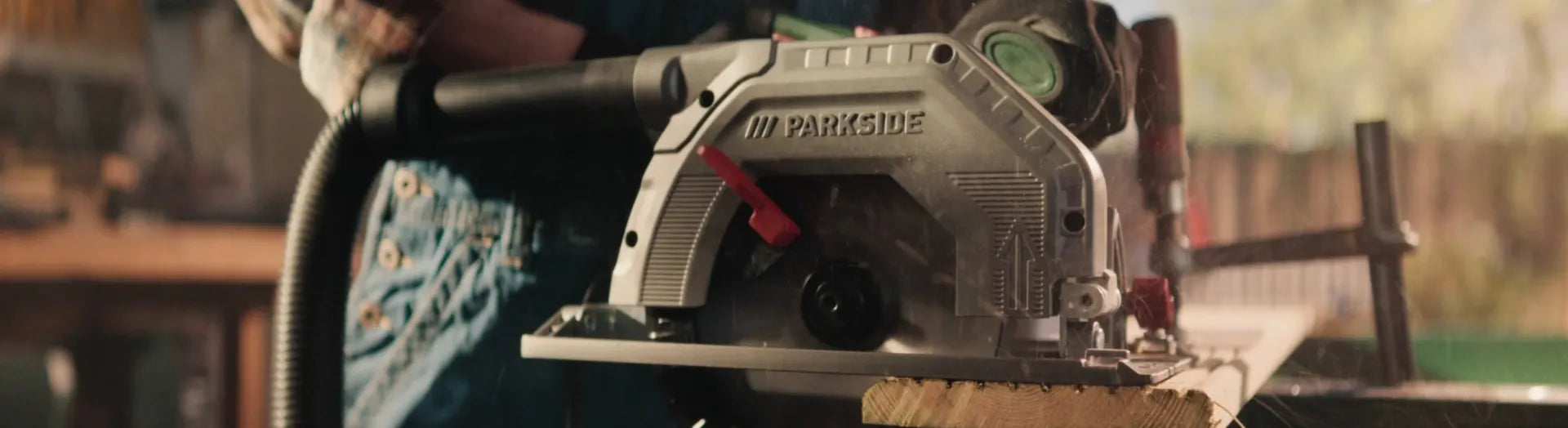 Une scie circulaire Parkside en action sur une planche, dans un atelier